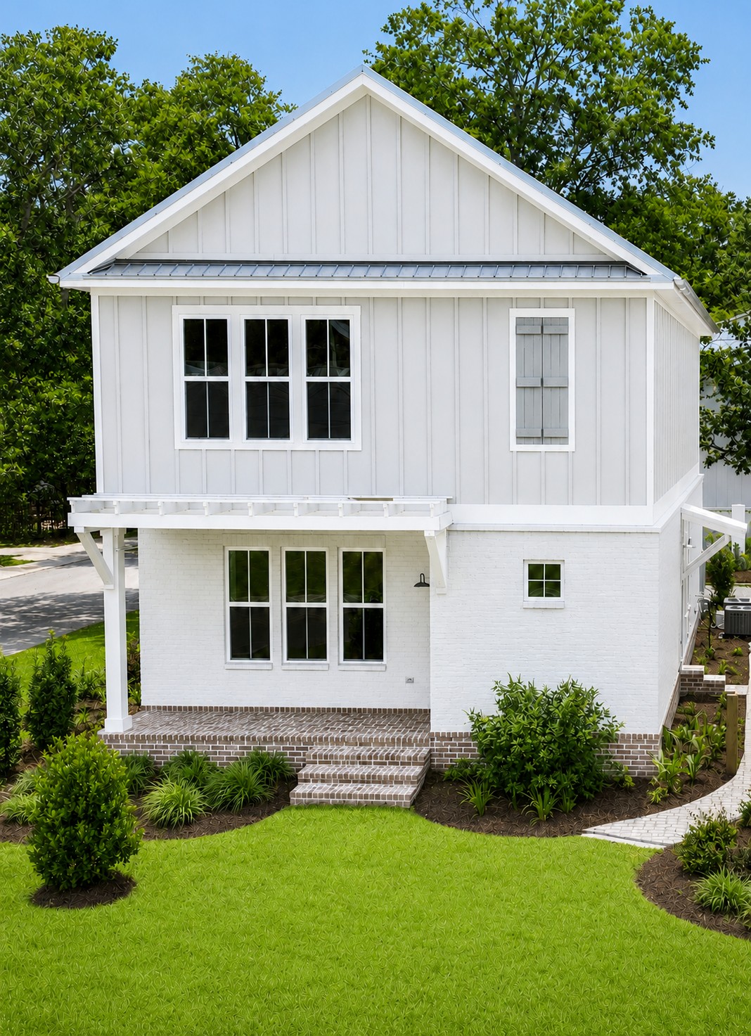 Rear exterior of a custom home with white board-and-batten siding, painted brick, metal roof accents, brick steps, and landscaping at 298 Porter Avenue in downtown Ocean Springs, Mississippi 39564.