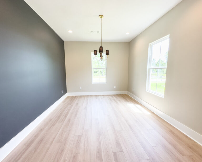 Formal dining room with a dark accent wall, light wood flooring, tall windows, and a modern chandelier at 12487 Alphabet Road in Florence Gardens, Gulfport, Mississippi 39503.