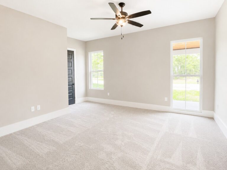 Downstairs guest bedroom with neutral carpet, large windows, a black interior door, and ceiling fan at 12487 Alphabet Road in Florence Gardens, Gulfport, Mississippi 39503.