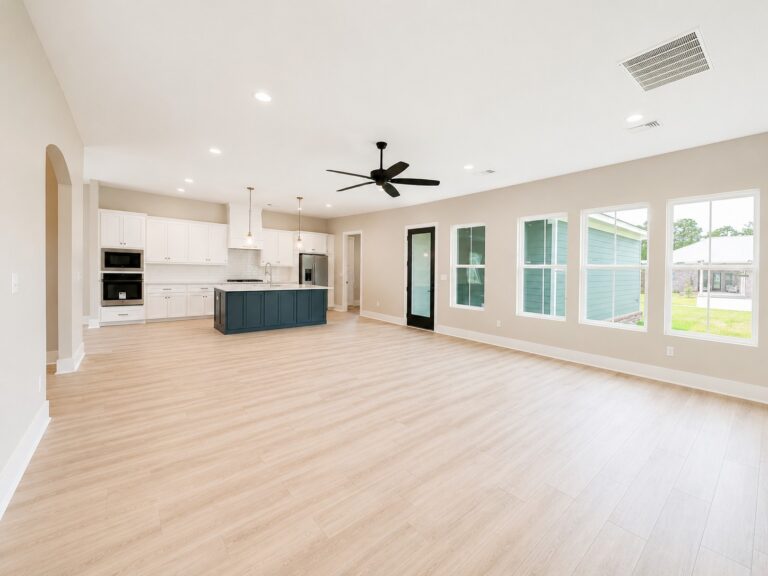 Open-concept living room and kitchen with light wood flooring, white cabinetry, a dark island, large windows, and a black ceiling fan at 12487 Alphabet Road in Florence Gardens, Gulfport, Mississippi 39503.