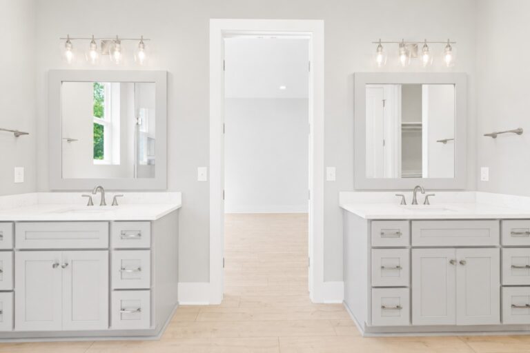 Primary bathroom with separate gray vanities, white countertops, framed mirrors, brushed-nickel fixtures, and light wood-look flooring at 298 Porter Avenue in downtown Ocean Springs, Mississippi 39564.
