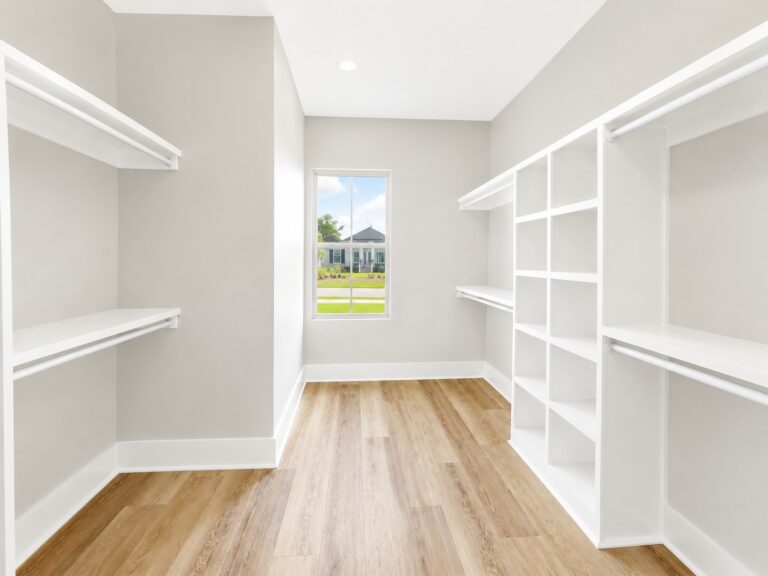 Custom walk-in primary closet with built-in white shelving, double hanging rods, a window, and wood-look flooring in the Cypress home at 12483 Alphabet Road in Florence Gardens, Gulfport, Mississippi 39503.