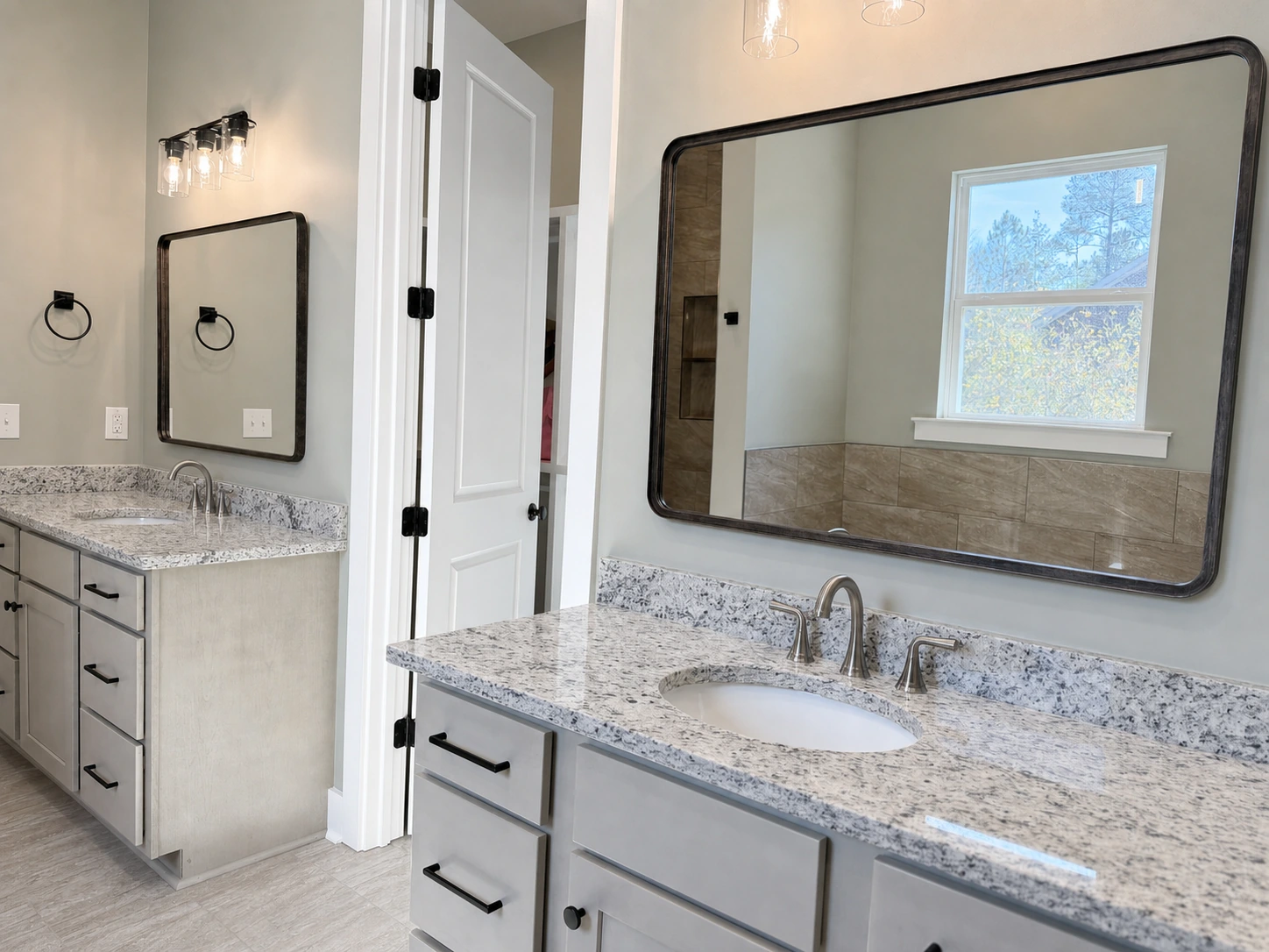 Bright bathroom with large framed mirrors, custom cabinetry with quartz countertops, and black hardware by BW Artisan Homes in Gulfport, MS.