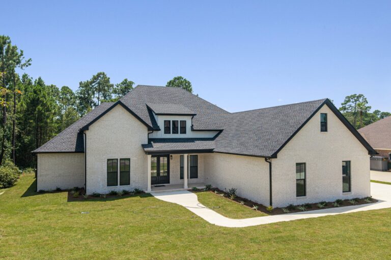 Front exterior view of a white brick custom home with black windows and covered porch by BW Artisan Homes in Gulfport, MS