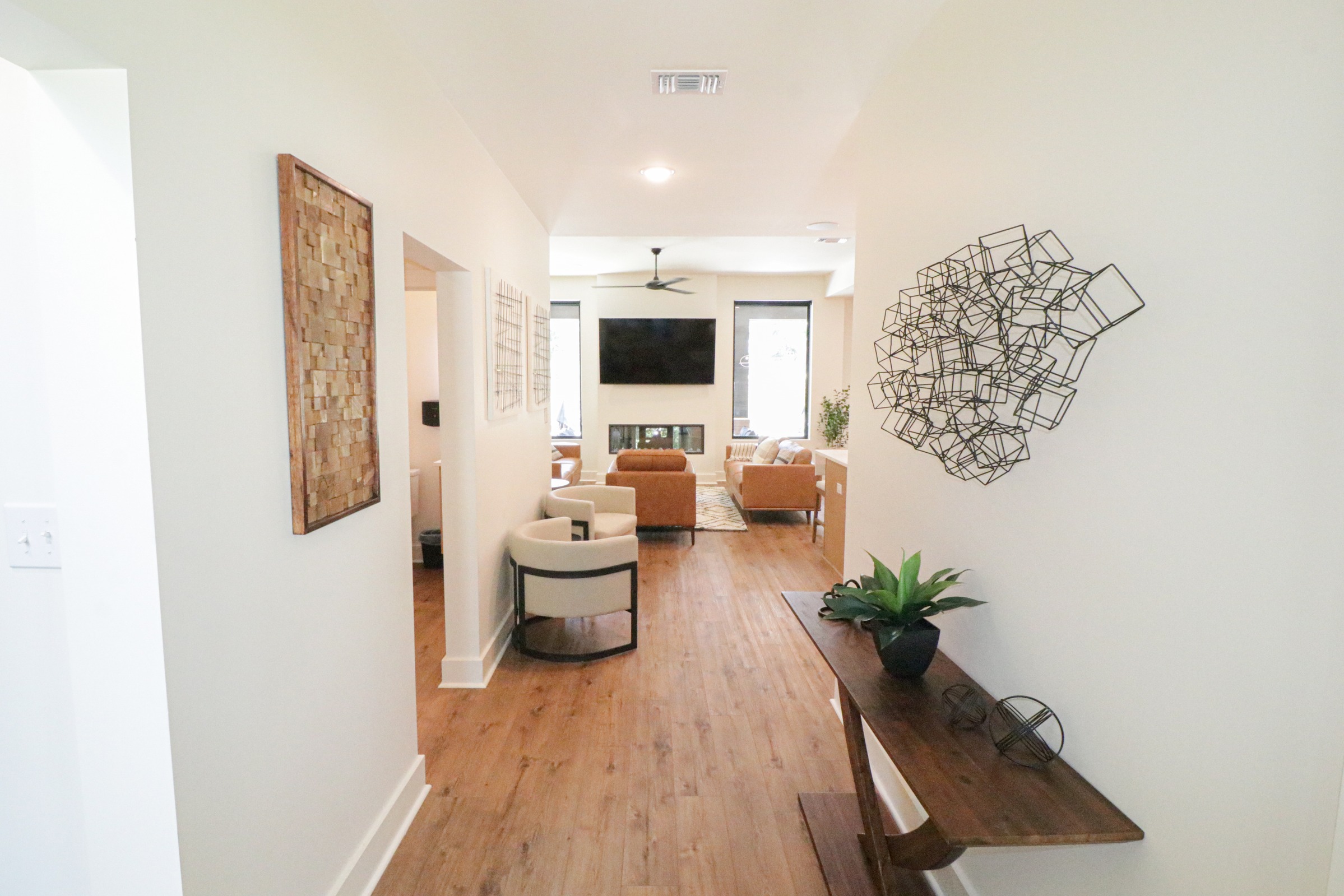Bright hallway leading to a living room with luxury vinyl plank flooring, black windows, stylish seating, and a fireplace, showcasing BW Artisan Homes craftsmanship in Gulfport.